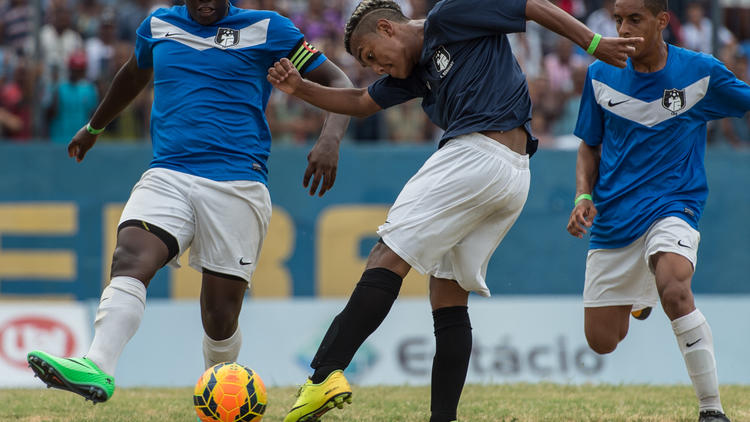 Un joueur de Vila Kennedy fait une frappe devant un adversaire de Cidade de Deus, le 15 février 2014 durant la finale de la Coupe des favelas, à Rio de Janeiro [Yasuyoshi Chiba / AFP]