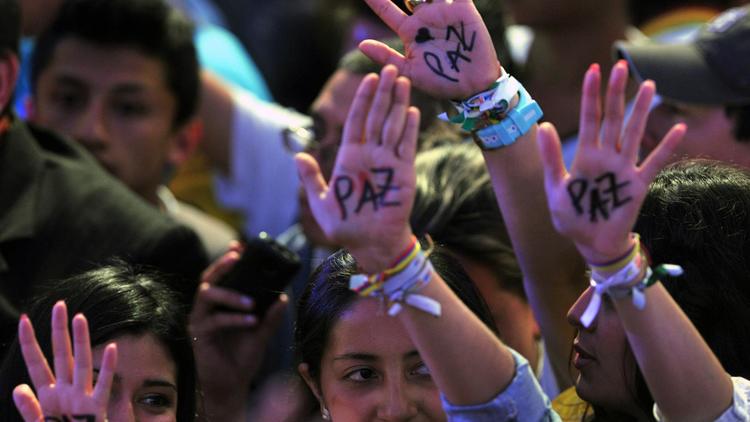 Des partisans du candidat colombien Juan Manuel Santos célèbrent sa victoire à l'élection présidentielle, le 15 juin 2014 à Bogota montrant la paume de leur mains où est écrit le mot "paix" [Guillermo Legaria / AFP]