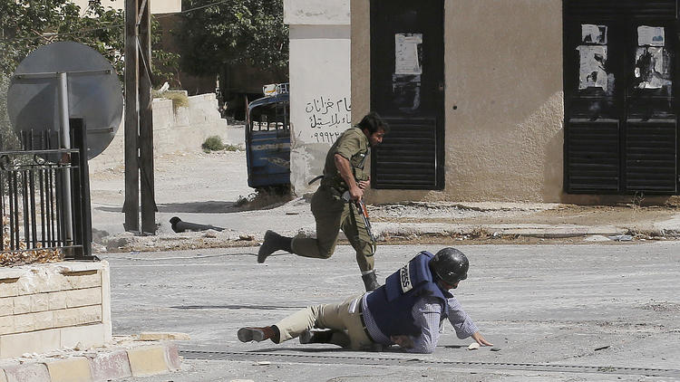 Le reporter de l'AFP Sammy Ketz à terre alors qu'un soldat syrien court pour échapper au tir d'un sniper le 18 septembre 2013 à Maaloula [Anwar Amro / AFP]
