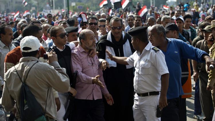 Un policier égyptien arrête un homme soupçonné d'être membre des Frères musulmans le 6 octobre 2013 sur la place Tahrir au Caire [Khaled Desouki / AFP]