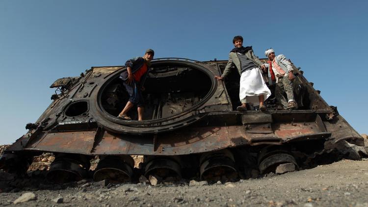 Des Yéménites se tiennent debout dans la carcasse d'un tank détruit lors de récents combats entre les forces gouvernementales et des rebelles chiites dans la province du nord-ouest Omran, le 8 juin 2014 [Mohammed Huwais / AFP]