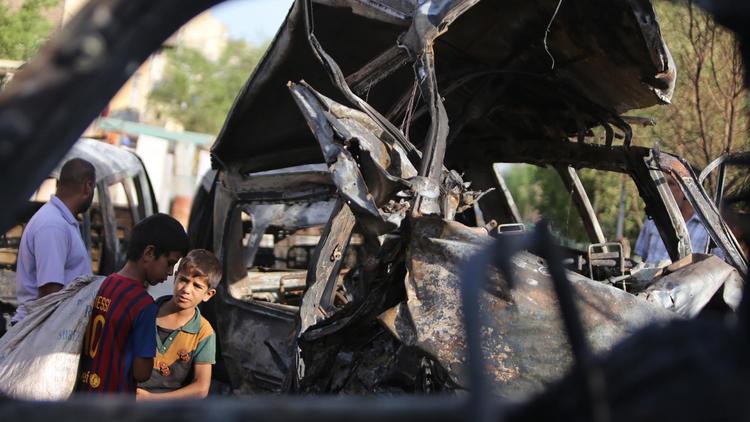 De jeunes Irakiens inspectent une voiture piégée à la bombe à Bagdad le 18 juin 2014 [Ahmad Al-Rubaye / AFP/Archives]