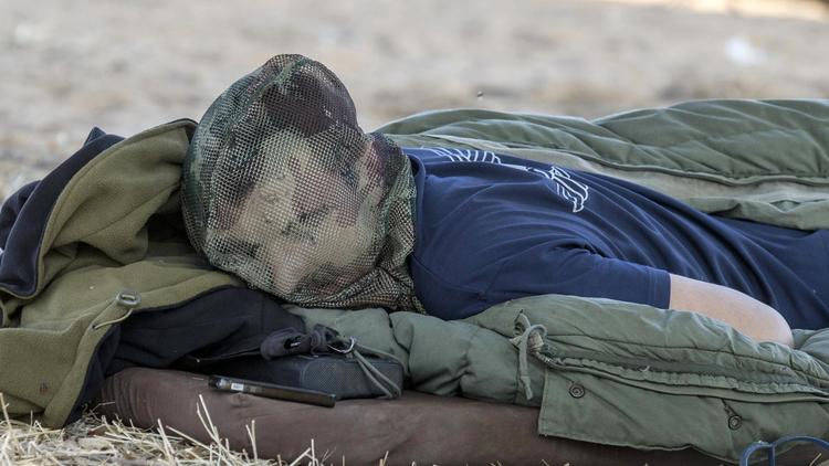 Un soldat israélien dort le visage couvert d'une moustiquaire près de la frontière avec la bande de Gaza, le 8 juillet 2014 [Jack Guez / AFP]