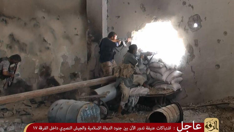 Photo d'écran relayée par le média djihadiste Welayat de Raqqa le 25 juillet 2014 montrant des membres de l'Etat islamique (EI) qui tirent sur des soldats pro-régime à Raqqa [ / Welayat Raqa/AFP]