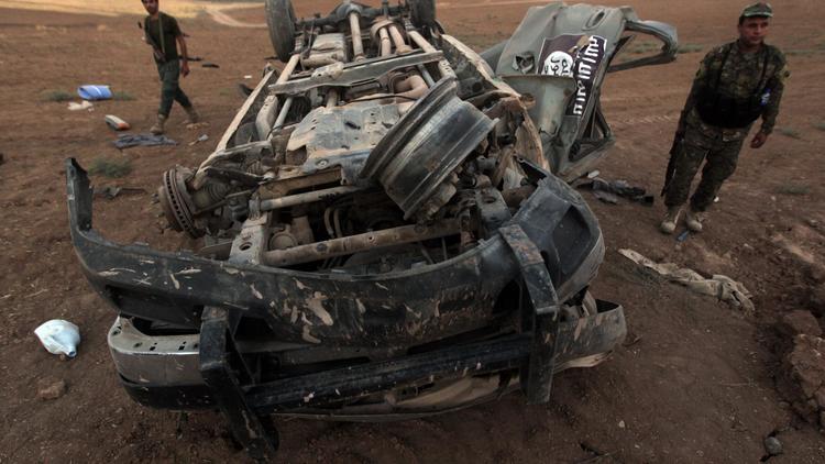 Des peshmergas inspectent l'épave d'un véhicule aux couleurs de l'Etat islamique, détruit par une frappe américaine, à Baqufa au nord de Mossoul, le 18 août 2014 en Iraq [Ahmad Al-Rubaye / AFP]