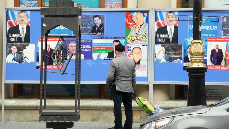Un homme regarde les affiches électorales des candidats à la présidentielle azerbaïdjanaise, le 7 octobre 2013 à Bakou [Tofik Babayev / AFP/Archives]