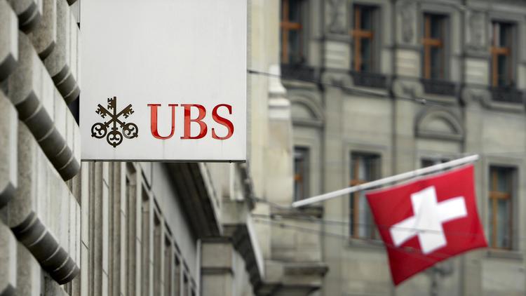 Un drapeau suisse derrière une enseigne de la banque UBS à Bâle [Fabrice Coffrini / AFP/Archives]