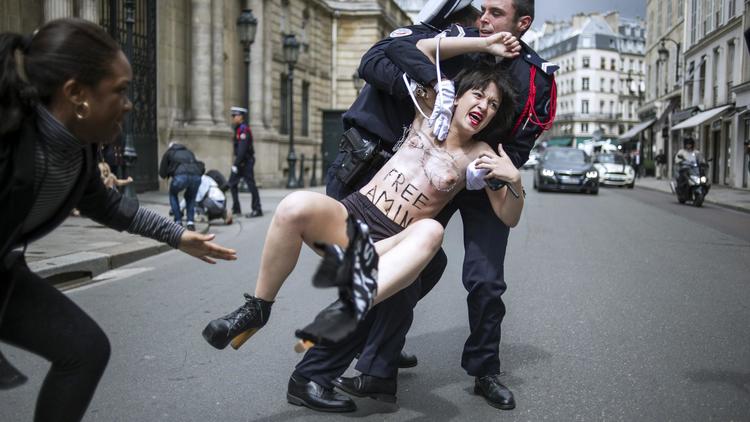 Un policier interpelle une militante Femen devant l'Elysée à Paris le 3 juillet 2013 [FRED DUFOUR / AFP]