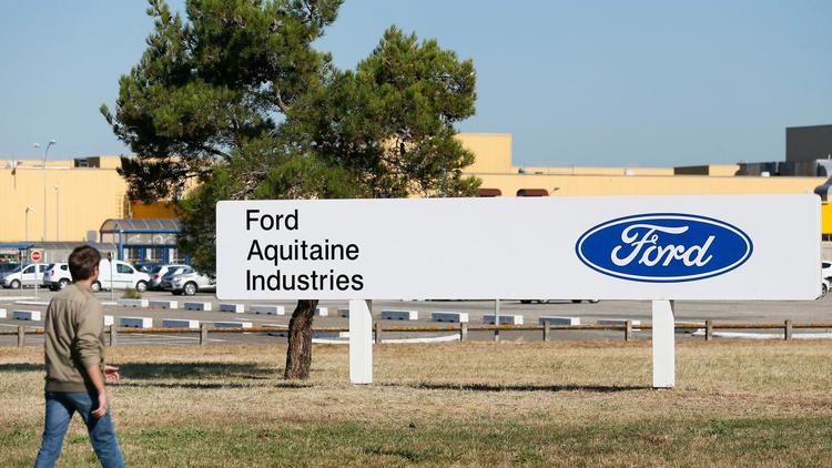 Un homme passe devant le logo du groupe américain Ford, réinstallé à l'entrée du site de Blanquefort (Gironde), le 31 juillet 2013 [Patrick Bernard / AFP]