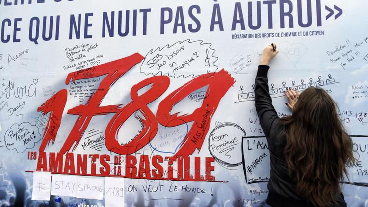 Une femme écrit un message de soutien sur l'affiche du spectacle "1789, les amants de la Bastille", le 9 novembre 2013, au lendemain d'une explosion [Kenzo Tribouillard / AFP/Archives]