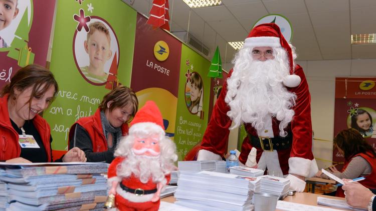 Un homme habillé en Père Noël auprès d'employés de La Poste lisant des lettres d'enfants, à Libourne le 21 novembre 2013 [Jean-Pierre Muller / AFP]