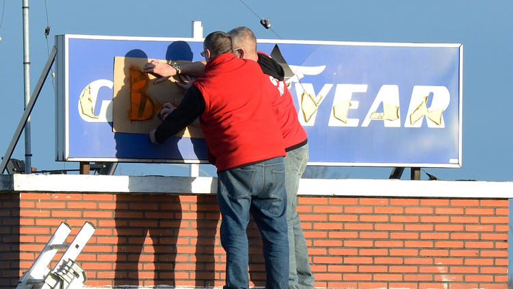 Des salariés de Goodyear installent une pancarte à l'entrée de leur usine à Amiens le 7 janvier 2014 [Denis Charlet / AFP]