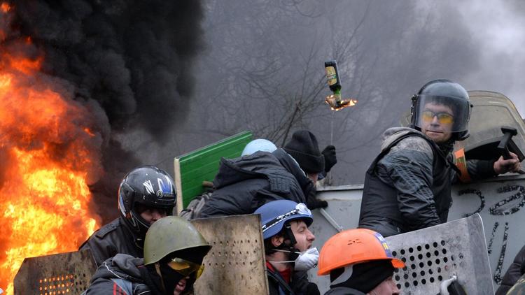 Des manifestants anti-gouvernementaux se protègent de tirs présumés de snipers, le 20 février 2014 à Kiev   [Sergei Supinsky / AFP/Archives]