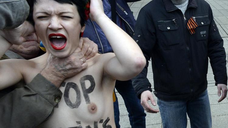 Un homme étrangle une manifestante du mouvement Femen devant le parlement de Crimée à Simféropol, le 6 mars 2014 [Alexander Nemenov / AFP]