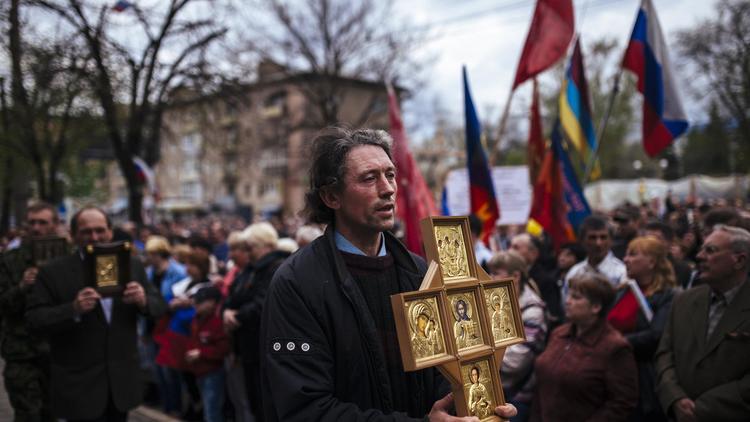 Un homme défile en tenant une icône orthodoxe, lors d'une manifestation pro-russe à Lugansk, en Ukraine, le 21 avril  [Dimitar Dilkoff / AFP]