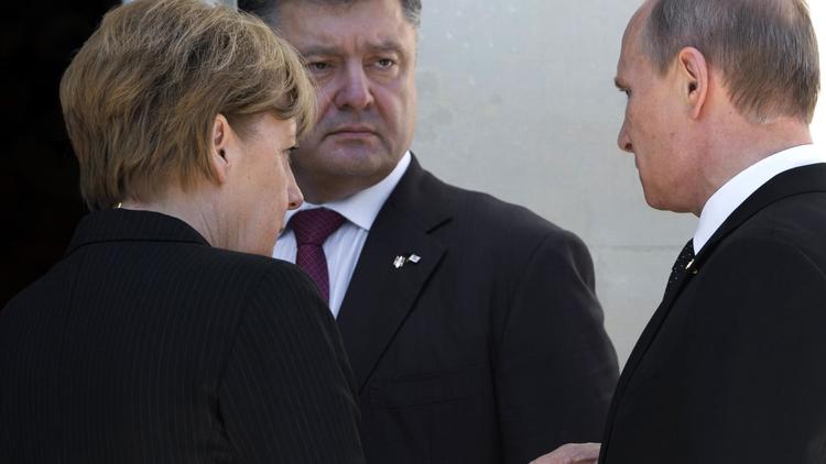 Le président ukrainien Piotr Porochenko (c) s'entretient avec le président russe Vladimir Poutine et la chancelière allemande Angela Merkel, lors de l'anniversaire du Débarquement le 6 juin 2014 au Chateau de Benouville [Saul Loeb / AFP]