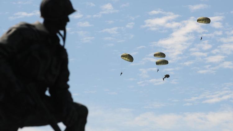 Des parachutistes militaires européens et américains sautent au-dessus de Sainte-Mère-Église, en Normandie, le 8 juin 2014 [Jean-Sébastien Evrard / AFP]