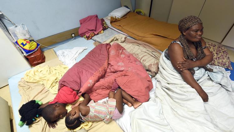 Une femme dort avec ses enfants dans un ancien bureau d'EDF, "réquisitionné" par des associations à Toulouse, le 9 juillet 2014 [Eric Cabanis / AFP]
