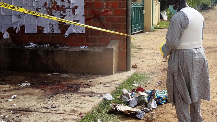 Un enquêteur de la police inspecte les lieux de l'attentat suicide à l'école polytechnique de l'Etat de Kano, qui a fait au moins 6 morts, le 30 juillet 2014 [Aminu Abubakar / AFP]