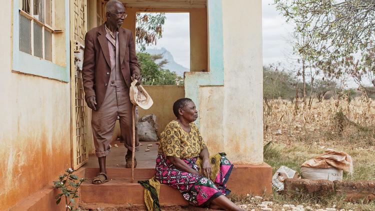 Mwamkono Mwavaka, dont le grand-père fut enrôlé de force comme porteur dans l'armée britannique pendant la Première Guerre mondiale, se tient sur le perron de sa maison avec sa femme, le 26 juillet 2014, à Taita Taveta, dans le parc national de Tsavo [Nichole Sobecki / AFP]