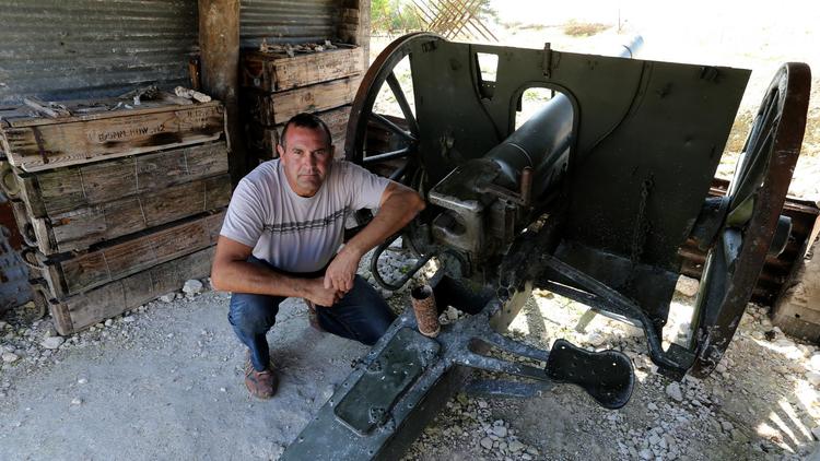 Eric Marchal, l'un des fondateurs de "La main de Massiges", pose à côté d'un canon dans les tranchées de la Première guerre mondiale [François Nascimbeni / AFP]