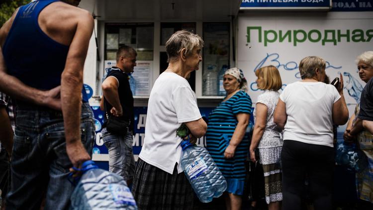 Bonbonnes de plastiques vides à la main, les habitants de Donetsk, patientent dans de longues files d'attente devant des kiosques qui vendent de l'eau minérale au litre, le 18 aout 2014 [Dimitar Dilkoff / AFP]