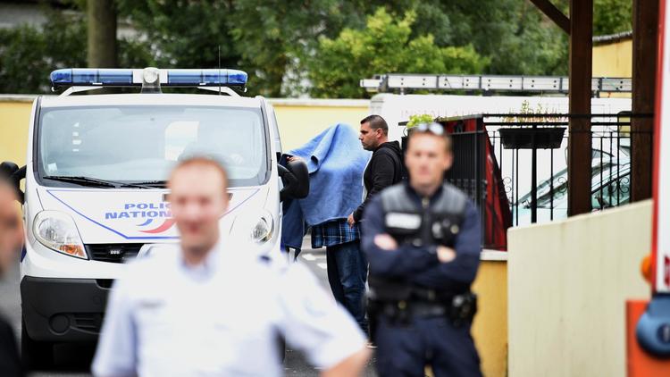 Un homme caché sous une est amené dans une véhicule de police devant l'hôtel où trois personnes ont été retrouvées mortes le 28 août 2014 à Draveil [Martin Bureau / AFP]