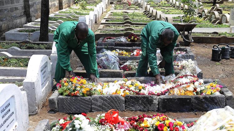 Le 26 septembre 2013, des employés d'un cimetière de Nairobi arrangent des fleurs sur la tombe du journaliste kényan Ruhila Adatia-Sood, tué lors de l'attaque du Westgate [Simon Maina / AFP]