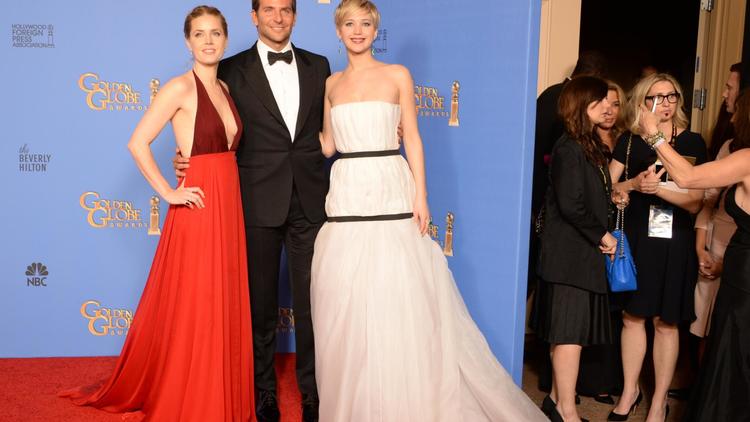 Les acteurs Amy Adams d'"American Bluff" Amy Adams (gauche), Bradley Cooper et Jennifer Lawrence, dont le film a été récompensé, posent lors de la cérémonie des Golden Globes à Beverly Hills le 12 janvier 2014 [Robyn Beck / AFP]