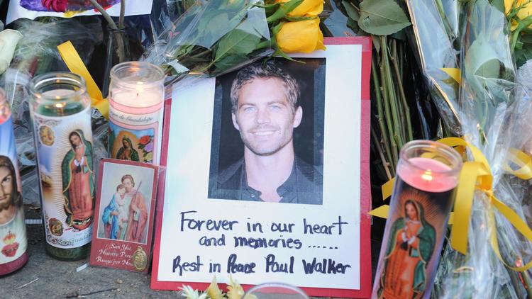 Une photo de l'acteur Paul Walker entourée de fleurs et de bougies déposées par des fans sur les lieux de l'accident qui lui a coûté la vie, le 1er décembre 2013 à Santa Clarita (Californie) [Robyn Beck / AFP/Archives]