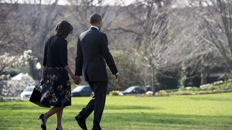 Le président américain Barack Obama, main dans la main avec la Première Dame Michelle Obama, sur les pelouses de la Maison-Blanche à Washington, DC, le 9 avril 2014 [Saul Loeb / AFP]
