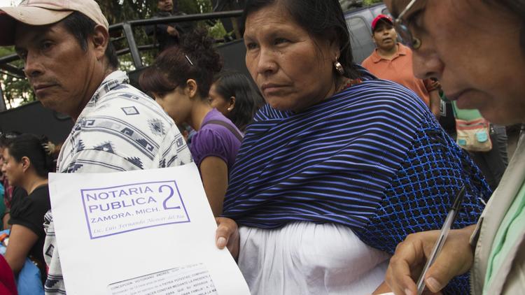 Une Mexicaine exhibe le contrat que les parents signaient en confiant la garde de leurs enfants au foyer "La Gran Familia"(la grande famille) où la police a fait un raid et libéré 596 personnes dont 458 enfants à Zamora, au Mexique le 16 juillet 2014  [Hector Guerrero / AFP]