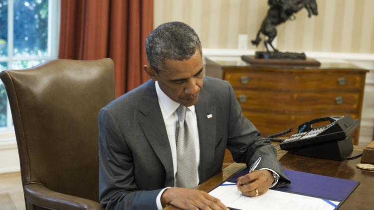 Le président américain Barack Obama signe le texte prévoyant une aide supplémentaire de 225 millions de dollars pour le système israélien de défense antimissile Iron Dome, le 4 août 2014 à la Maison Blanche [Saul Loeb / AFP]