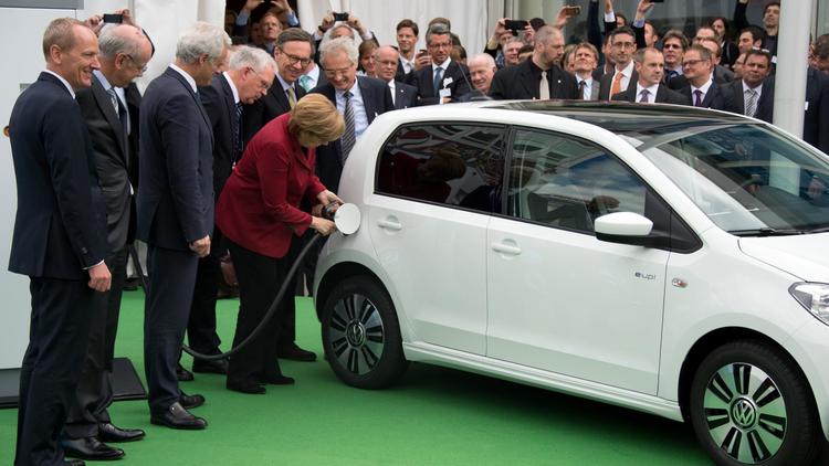 La chancelière Angela Merkel branche une voiture électrique, le 27 mai 2013 à Berlin, lors d'un congrès international sur l'électromobilité [Johannes Eisele / AFP]