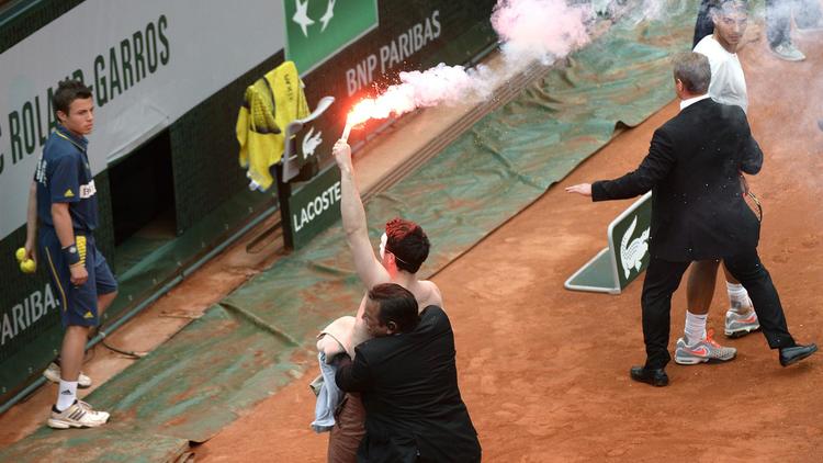 Le service de sécurité de Roland Garros évacue un homme opposé au mariage gay portant un fumigène lors de la finale opposant Rafael Nadal à David Ferrer le 9 juin 2013 à Paris [Martin Bureau / AFP]