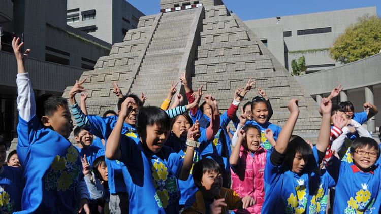 Des élèves d'une école primaire taiwanaise s'amusent devant une réplique d'une pyramide maya, le 21 décembre 2012 à Taichung