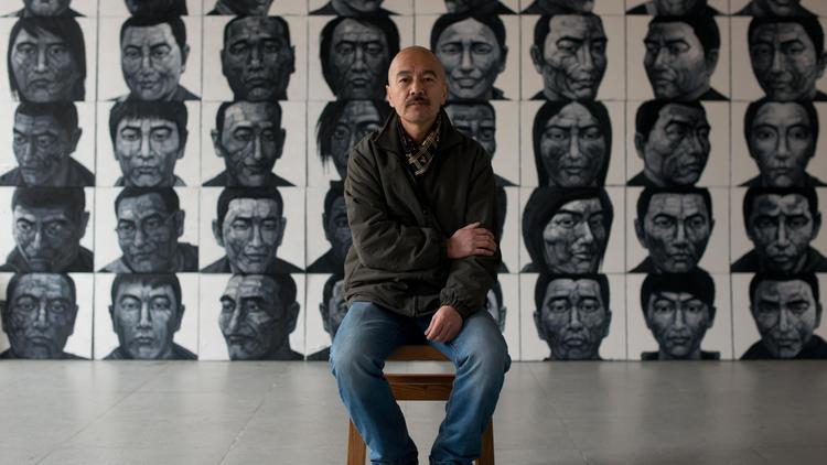 Le peintre Liy Yi, le 21 février 2013 dans son atelier dans les environs de Pékin, devant les portraits de moines tibétains qui se sont immolés [Ed Jones / AFP]