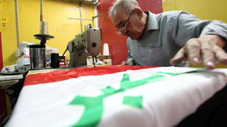 Un tailleur irakien coud un drapeau national dans son atelier à Bagdad, le 20 septembre 2012 [Sabah Arar / AFP]