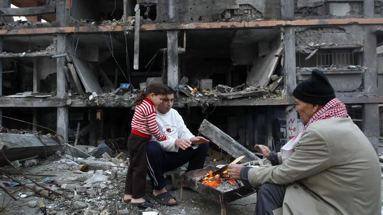Des palestiniens se réchauffent le 21 décembre 2012 près des décombres de maisons détruites en novembre lors des affrontements avec les forces israéliennes [Mohammed Abed / AFP/Archives]