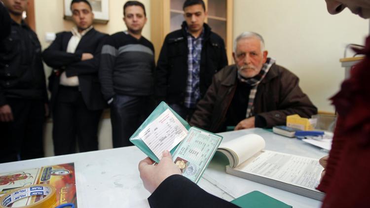 Un employé de la Commission électorale centrale palestinienne (CEC) vérifie les documents d'un habitant de Gaza, le 11 février 2013 [Mohammed Abed / AFP]