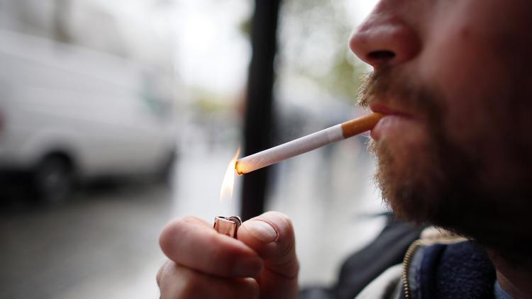Un homme allume une cigarette [Kenzo Tribouillard / AFP/Archives]