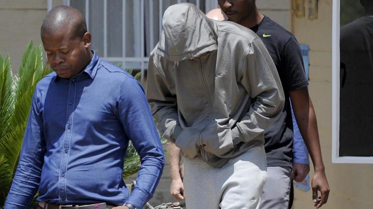 Oscar Pistorius, escorté par des policiers, quitte le commissariat de police pour être mis en détention, le 14 février 2013 à Pretoria [ / AFP]