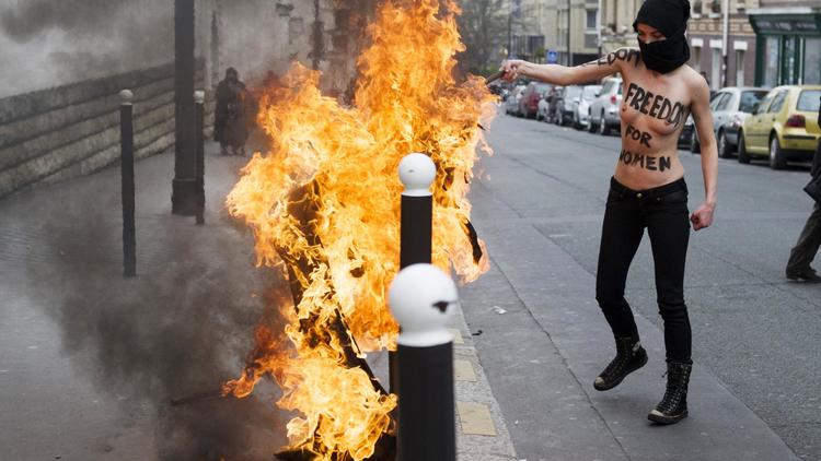 Une féministe du mouvement des Femen brûle le drapeau salafiste devant la Grande Mosquée de Paris [Fred Dufour / AFP]