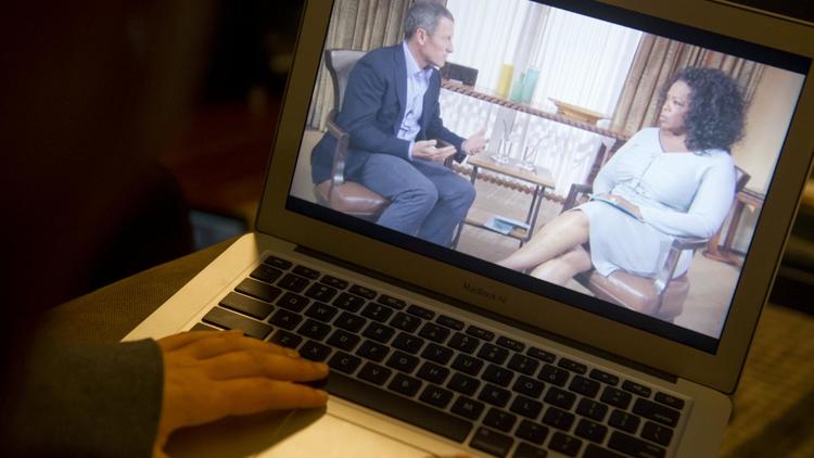 Une personne regarde sur son ordinateur l'interview du cycliste Lance Armstrong par Oprah Winfrey, le 17 janvier 2013 à Washington [Saul Loeb / AFP]