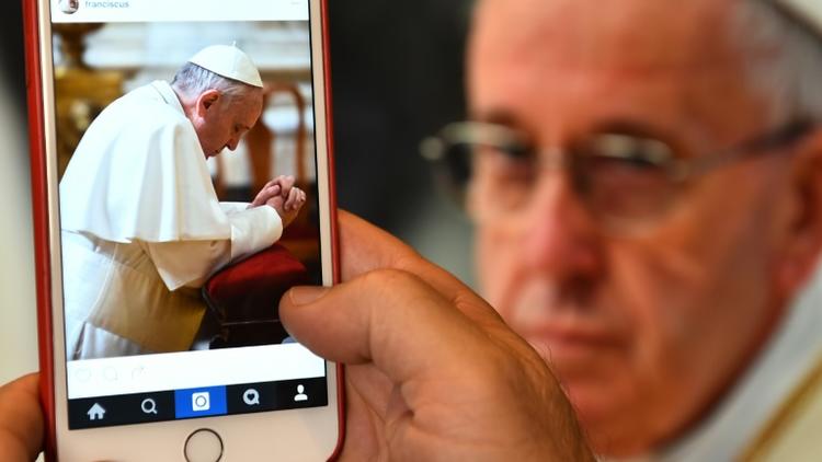 Un homme regarde le compte Instagram du pape sur son écran de portable, le 19 mars 2016 à Rome [GABRIEL BOUYS / AFP]