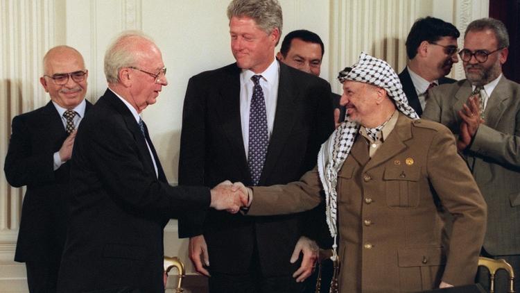 Le 28 septembre 1995, le président américain Bill Clinton (C) observe le premier ministre israélien Yitzhak Rabin (2e D) et Yasser Arafat (2e D), dirigeant de l'OLP, se serrer la main après la signature d'un accord, à Washington. [LUKE FRAZZA / AFP/Archives]