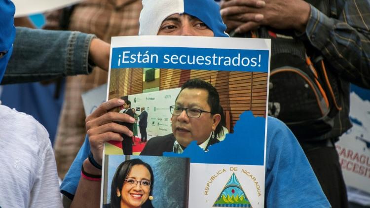 Un Nicaraguayen brandit une pancarte de soutien aux journalistes Miguel Mora et Lucia Pineda, accusés de terrorisme par le régime de Daniel Ortega, lors d'une manifestation le 22 décembre 2018 à San José au Costa Rica [Ezequiel BECERRA / AFP]