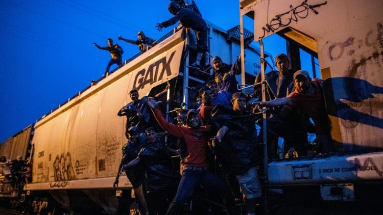 Des migrants illégaux agrippés à un train de marchandises en direction des Etats-Unis, traversent de nuit le village de Las Patronas, le 9 août 2018 dans l'Etat du Veracruz, au Mexique [RONALDO SCHEMIDT / AFP]