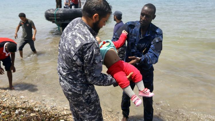 Des membres de la sécurité libyenne portent le corps d'un bébé dans la ville d'al-Hmidiya, après le naufrage au large de la Libye d'une embarcation de migrants dont 100 sont toujours portés disparus, le 29 juin 2018  [Mahmud TURKIA / AFP]