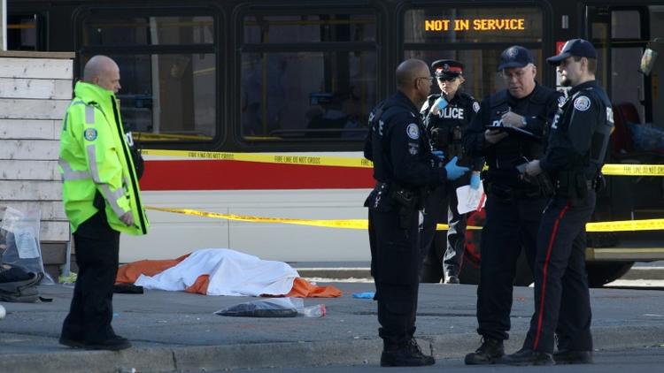 Des policiers près d'un corps caché par un drap, le 23 avril 2018 à Toronto, au Canada, après qu'un homme au volant d'une camionnette a fauché une dizaine de piétons  [Lars Hagberg / AFP]